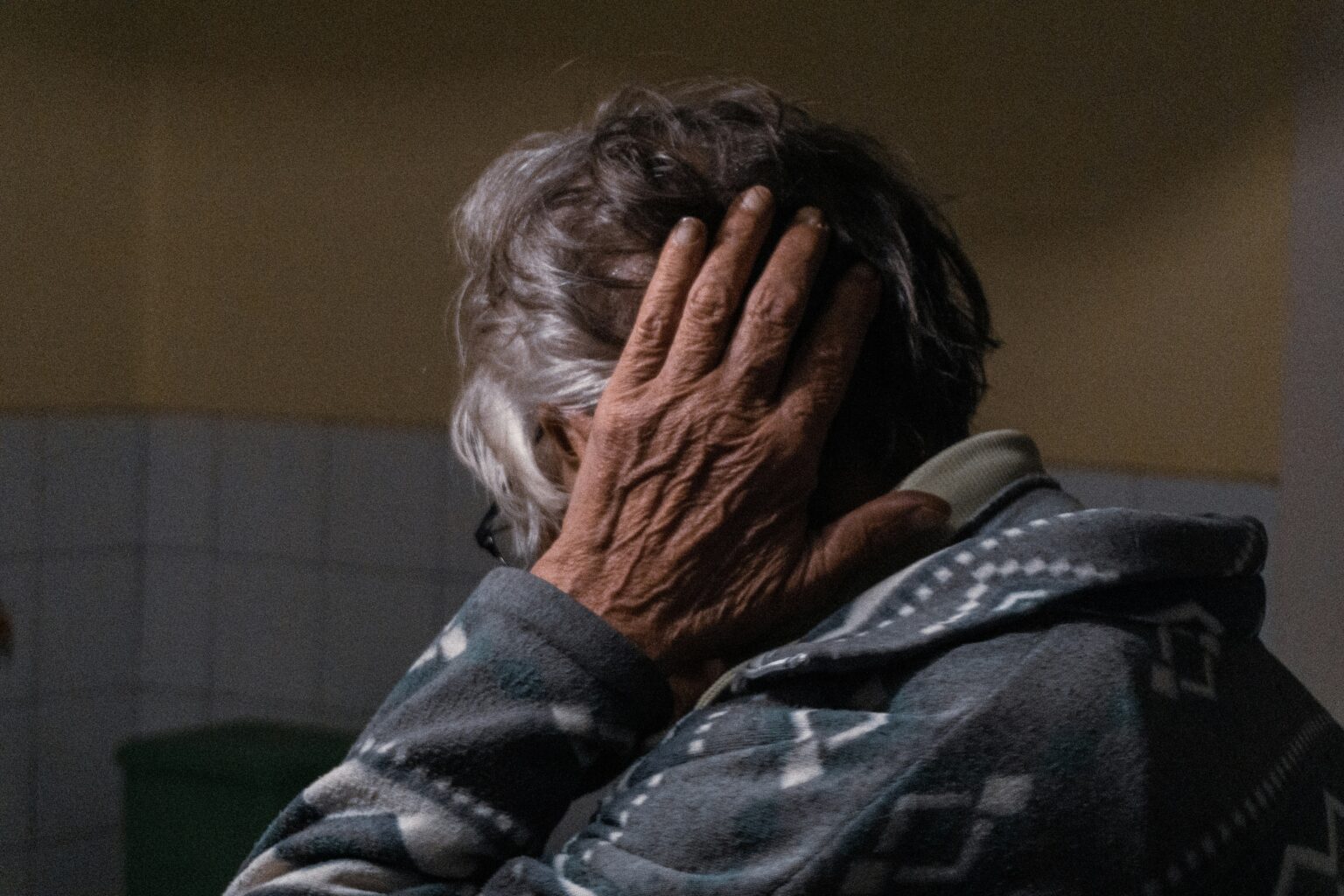 An elderly person covering their ear An elderly person covering their ear